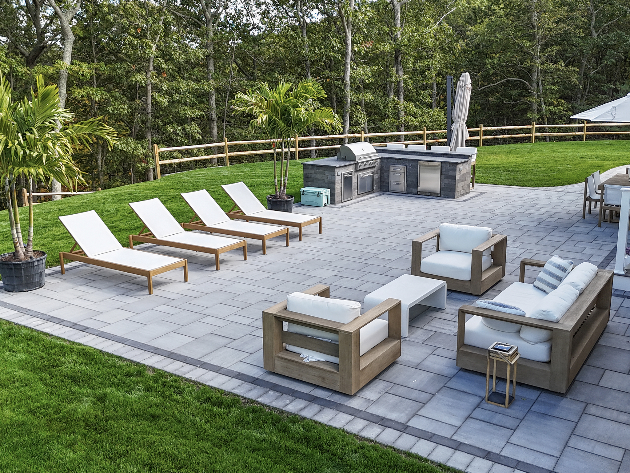 Large Cambridge paver patio with built-in outdoor kitchen, lounge chairs, and outdoor sofa set — Suffolk County NY hardscape contractor