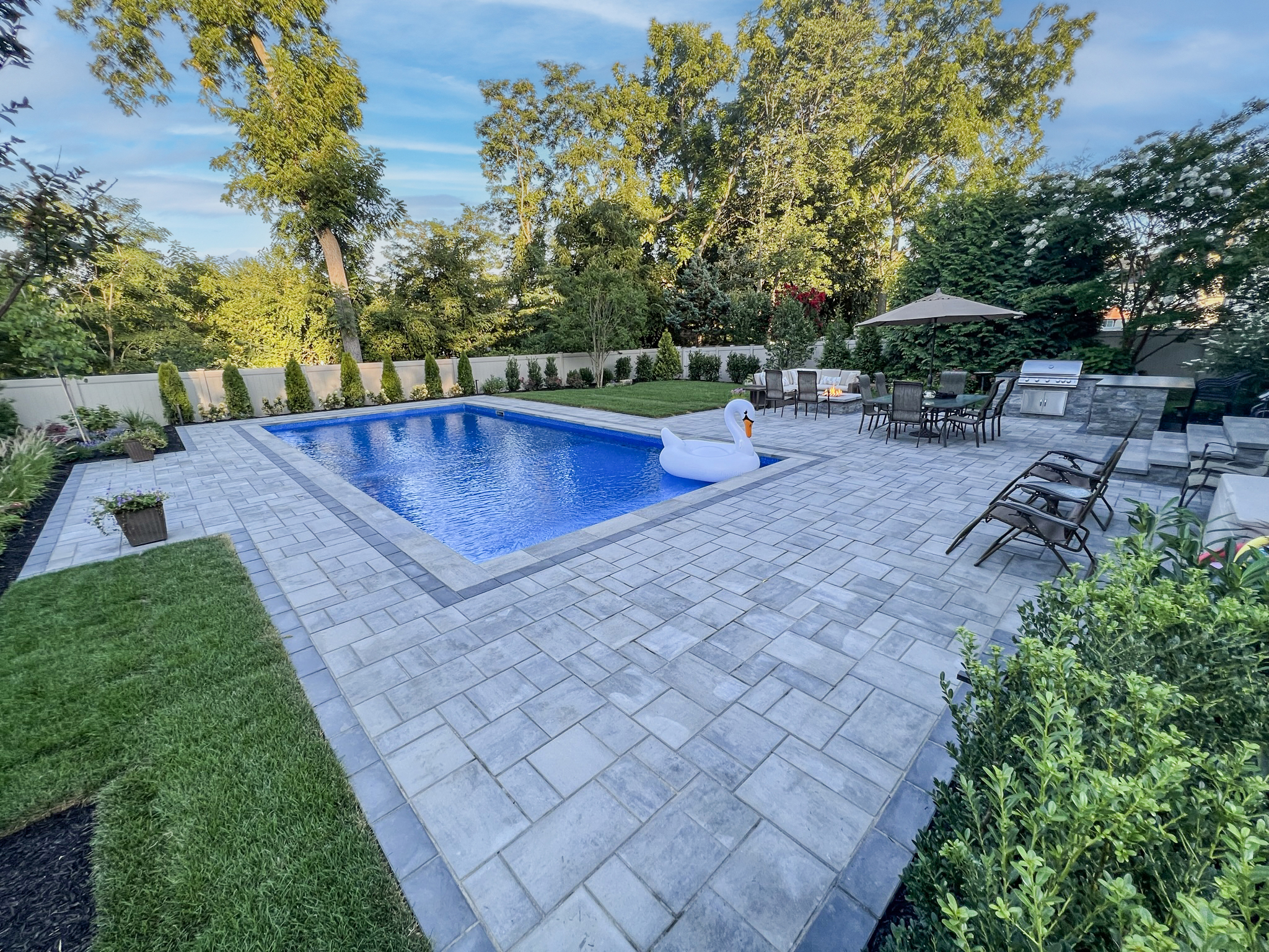 Inground pool with Cambridge paver surround, outdoor kitchen, pergola, and landscaped backyard — Long Island NY patio and pool contractor