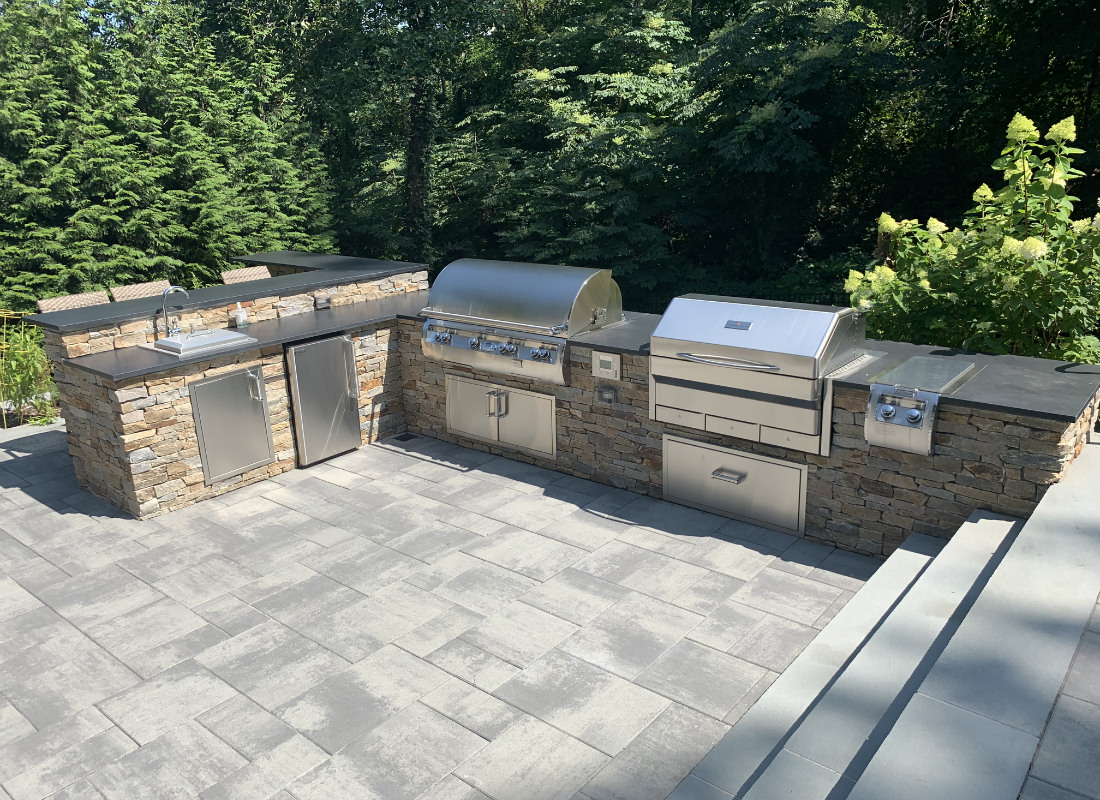 Large outdoor kitchen with sink, BBQ, smoker, and storage