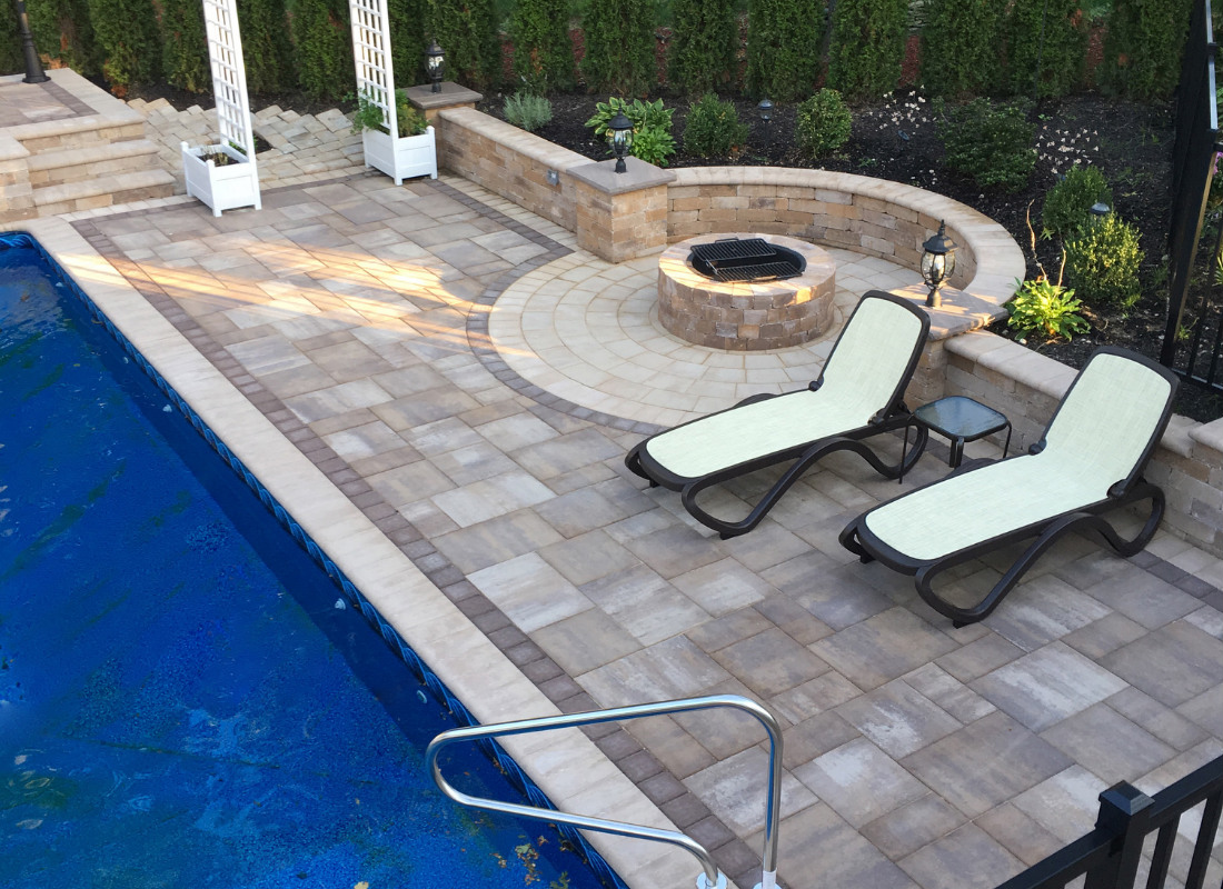 Side of pool with brick fire pit and two lounge chairs