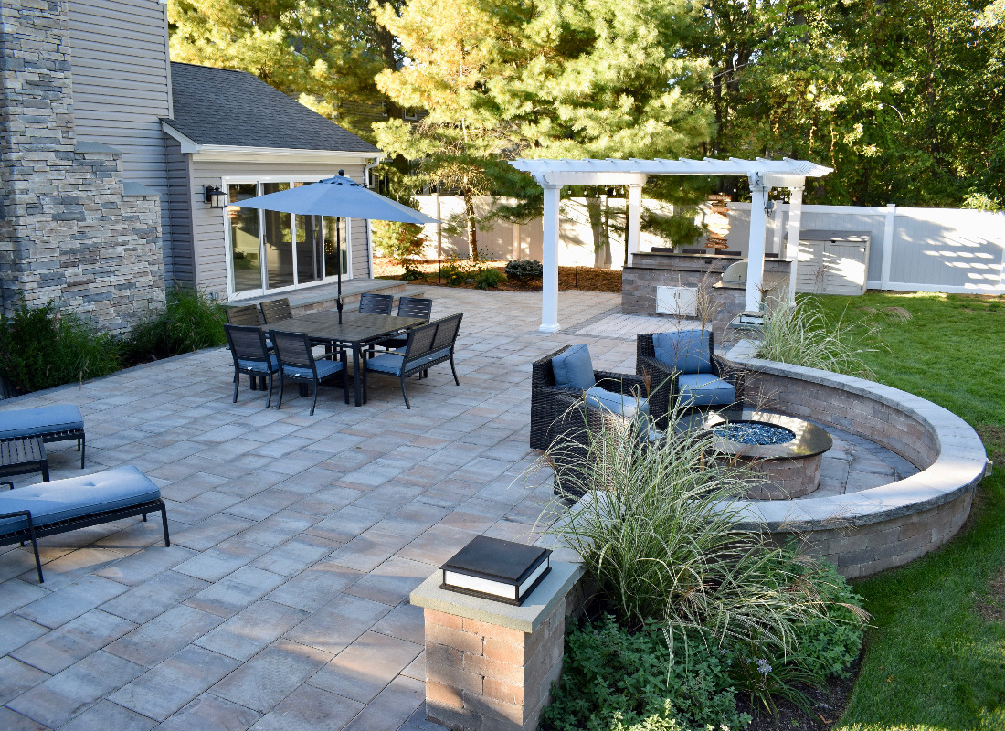 large square stone patio with half moon feature with seating and outdoor fireplace