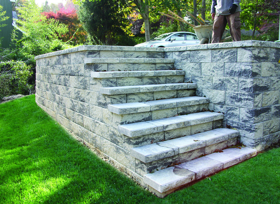 gray stone retaining wall and staircase to elevate to driveway from the home