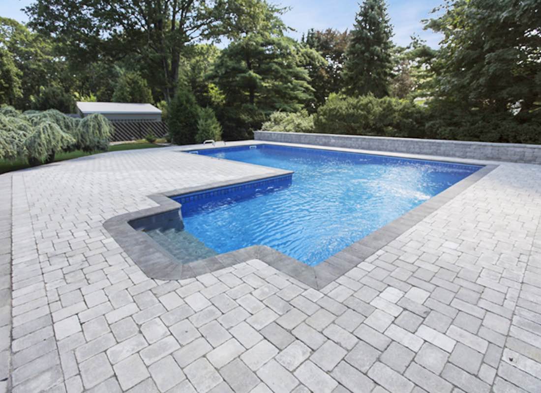 Gunite pool installation Northport — rectangular in-ground pool with paving stone surround