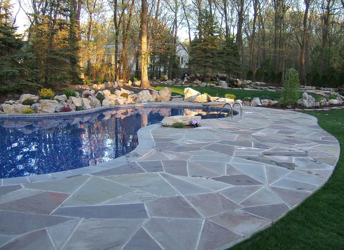 Pool installation in progress Northport NY — landscaped pool with natural stone surround