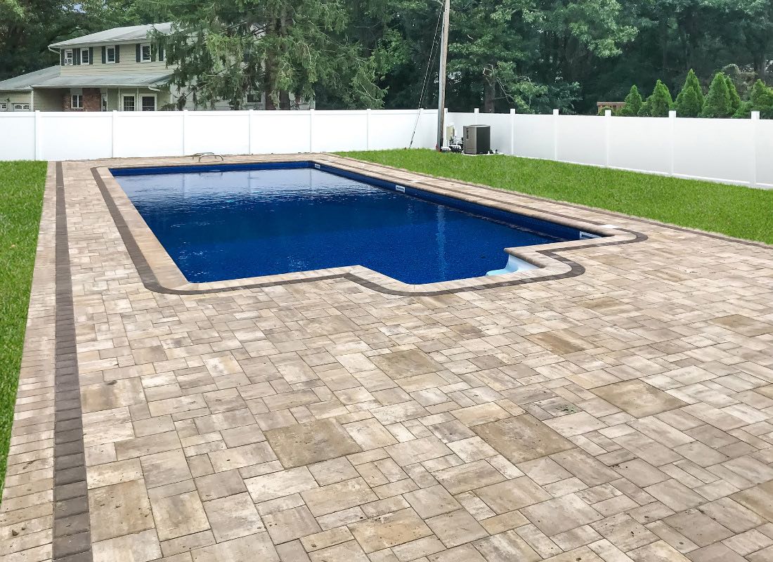Finished pool installation Northport — blue paving stone deck with white fence surround