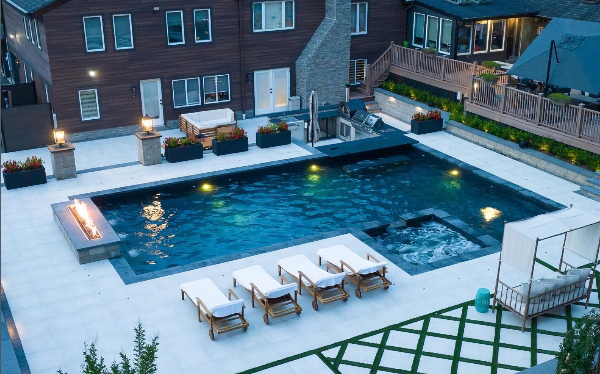 Crystal blue swimming pool surrounded by outdoor furniture and a wrap-around home.